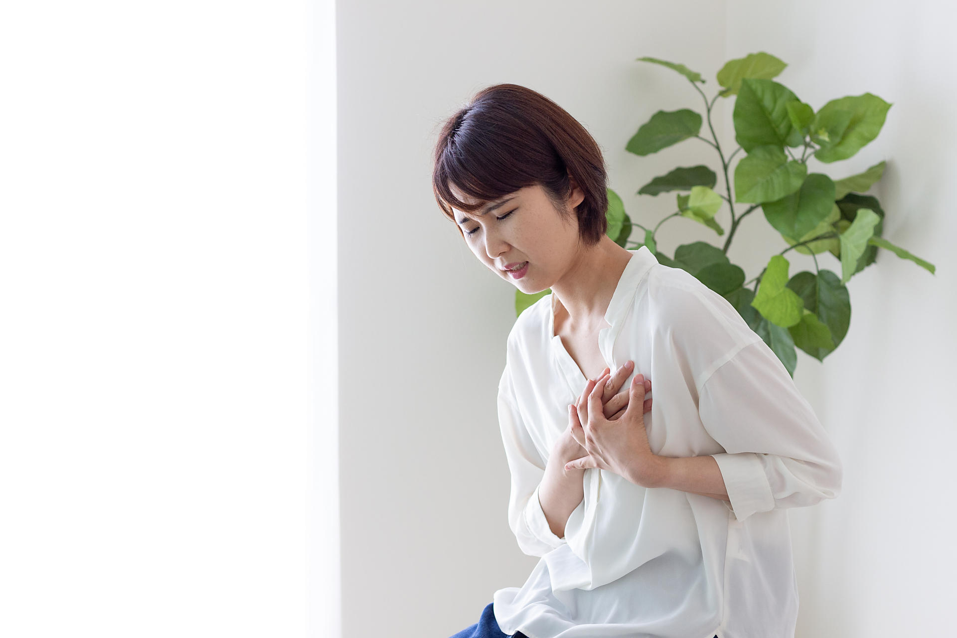 心臓を押さえる人の画像